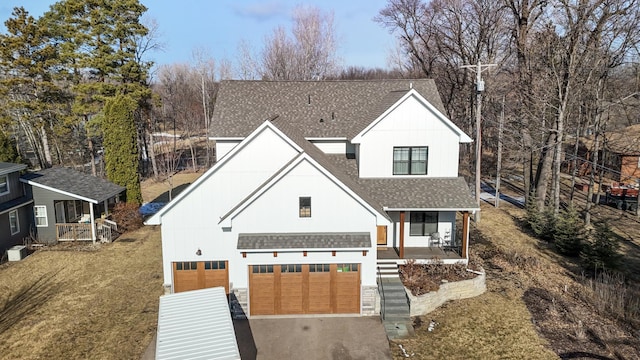 view of front of house with cooling unit, a garage, a front lawn, and a porch