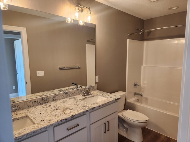 full bathroom featuring wood-type flooring, vanity, toilet, tub / shower combination, and a textured ceiling