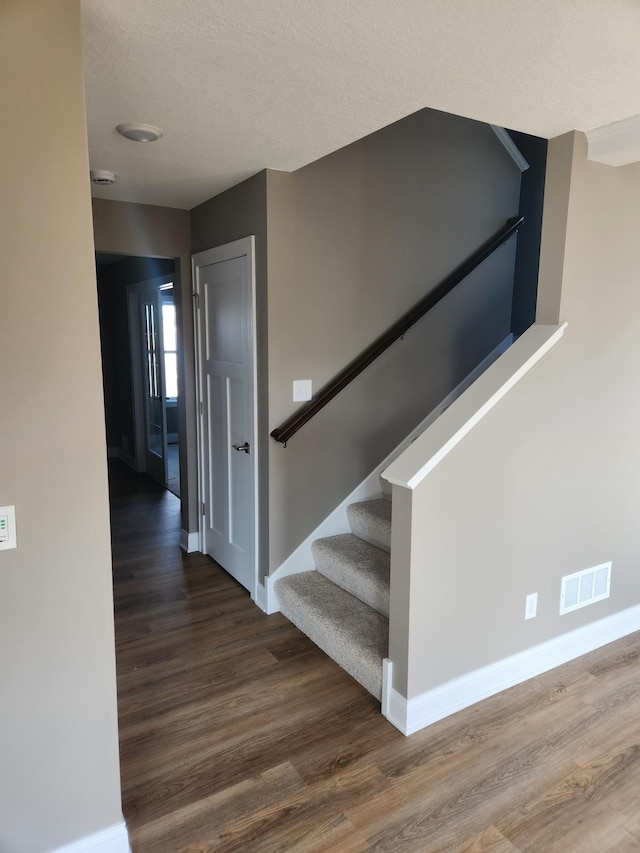 staircase with wood-type flooring and a textured ceiling