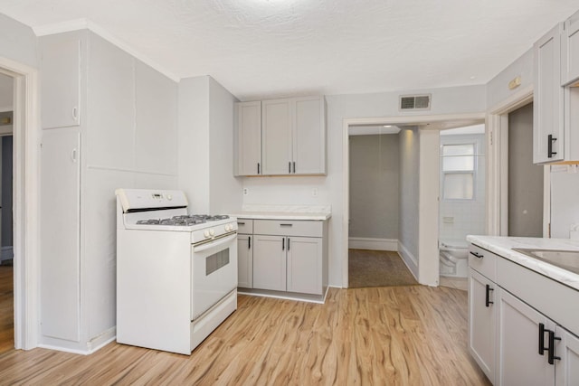 kitchen featuring sink, light hardwood / wood-style flooring, a textured ceiling, and gas range gas stove