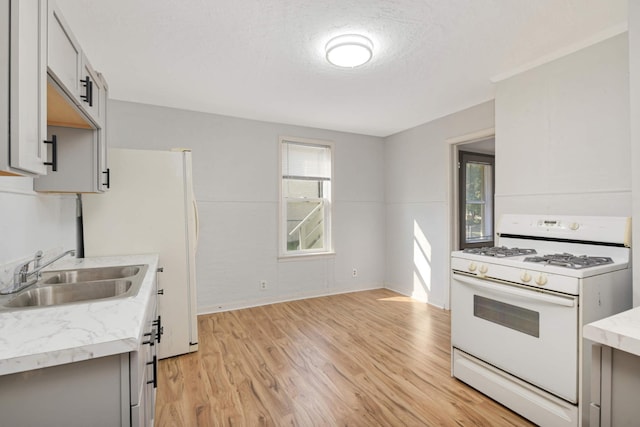 kitchen with sink, a textured ceiling, gray cabinets, white appliances, and light hardwood / wood-style floors