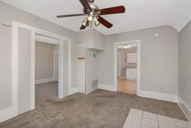 unfurnished bedroom featuring ceiling fan, light colored carpet, connected bathroom, and a closet