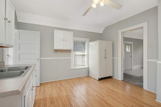 kitchen featuring sink, light wood-type flooring, white refrigerator, ceiling fan, and white cabinets