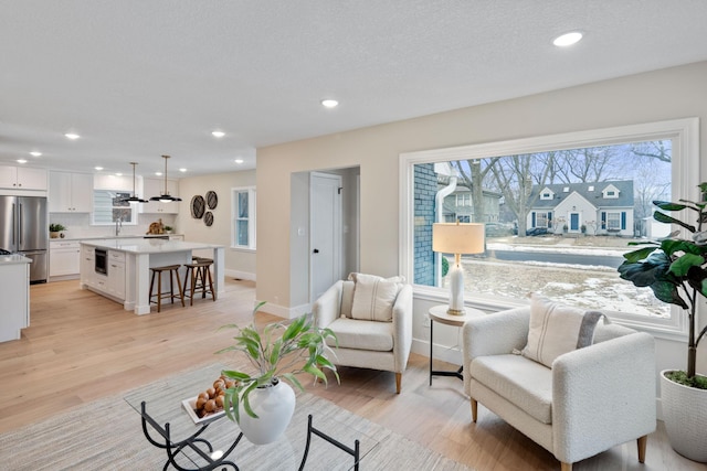 living room featuring sink, light hardwood / wood-style flooring, and a textured ceiling