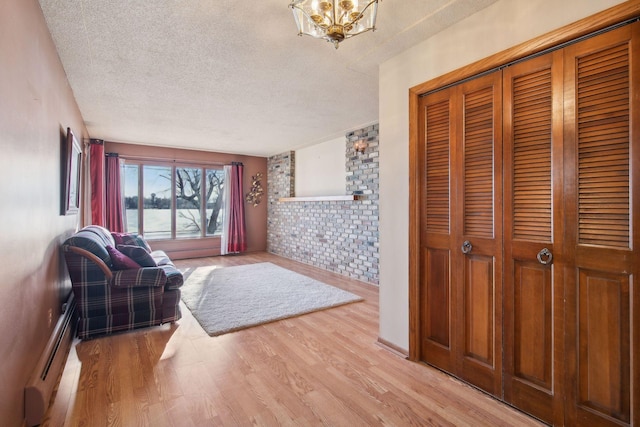 foyer entrance with an inviting chandelier, a baseboard heating unit, light hardwood / wood-style flooring, and a textured ceiling