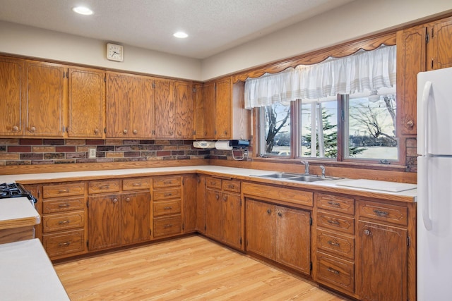 kitchen with sink, light hardwood / wood-style floors, a textured ceiling, and white refrigerator