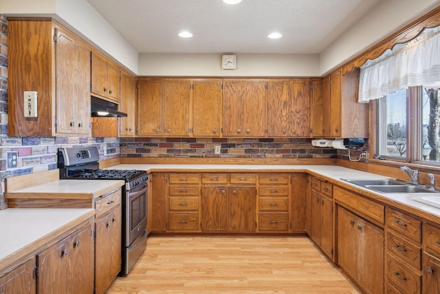 kitchen featuring light hardwood / wood-style floors, sink, decorative backsplash, and stainless steel gas stove