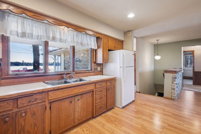 kitchen with sink, decorative light fixtures, a textured ceiling, light wood-type flooring, and white fridge