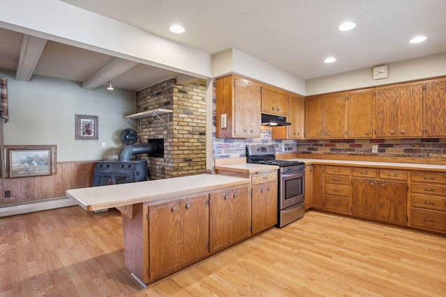 kitchen featuring light hardwood / wood-style floors, gas range, kitchen peninsula, beamed ceiling, and a wood stove