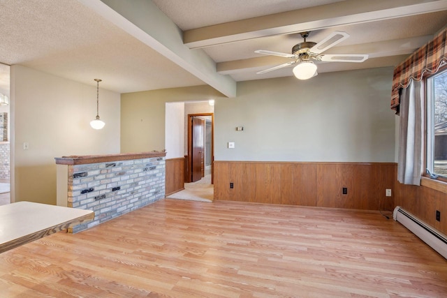 interior space featuring wood walls, a baseboard radiator, beam ceiling, a textured ceiling, and light wood-type flooring