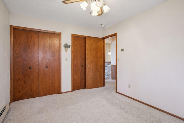 unfurnished bedroom with ceiling fan, a baseboard heating unit, a textured ceiling, light colored carpet, and multiple closets