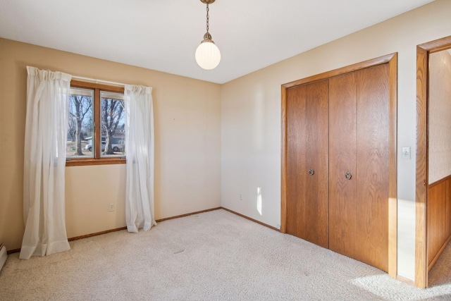 unfurnished bedroom with a baseboard heating unit, light colored carpet, and a closet