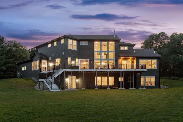 back house at dusk with a lawn and a deck