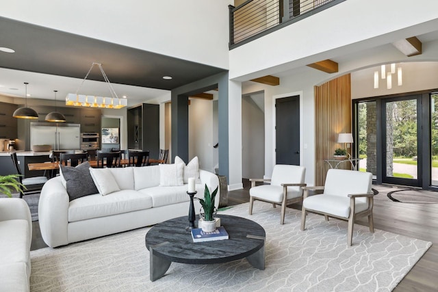 living room featuring beam ceiling, hardwood / wood-style floors, and a high ceiling