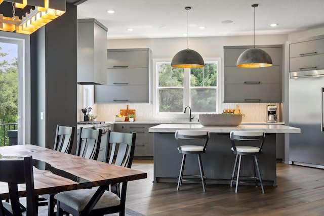 kitchen with a center island, built in refrigerator, gray cabinets, and island range hood