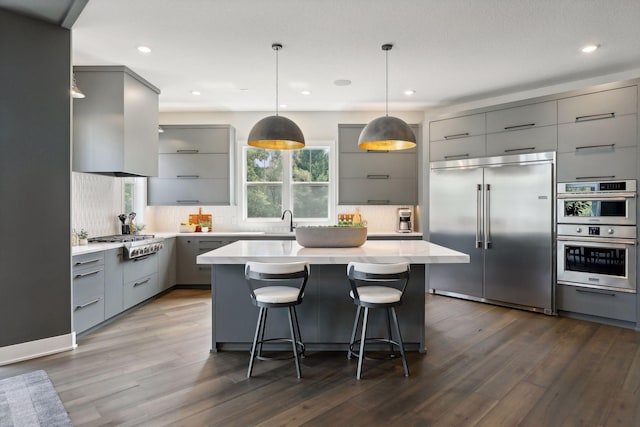 kitchen featuring gray cabinetry, extractor fan, a kitchen island, and appliances with stainless steel finishes