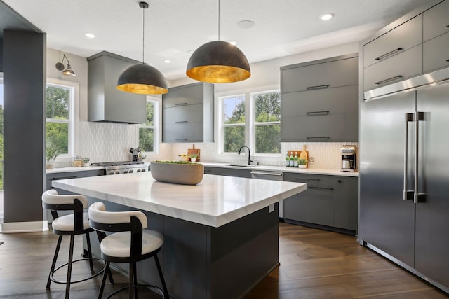 kitchen featuring a center island, appliances with stainless steel finishes, gray cabinets, and wall chimney range hood