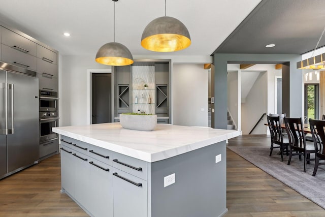 kitchen featuring gray cabinetry, decorative light fixtures, and stainless steel appliances