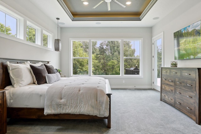 carpeted bedroom with access to exterior and a tray ceiling