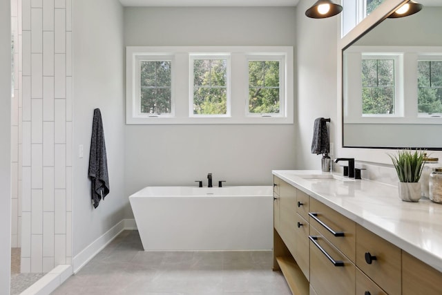 bathroom with tile patterned flooring, vanity, a healthy amount of sunlight, and a tub to relax in