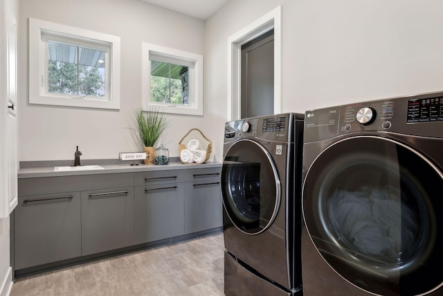 laundry area with cabinets, washing machine and dryer, and sink