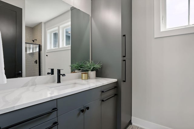 bathroom with vanity, a tile shower, and a wealth of natural light