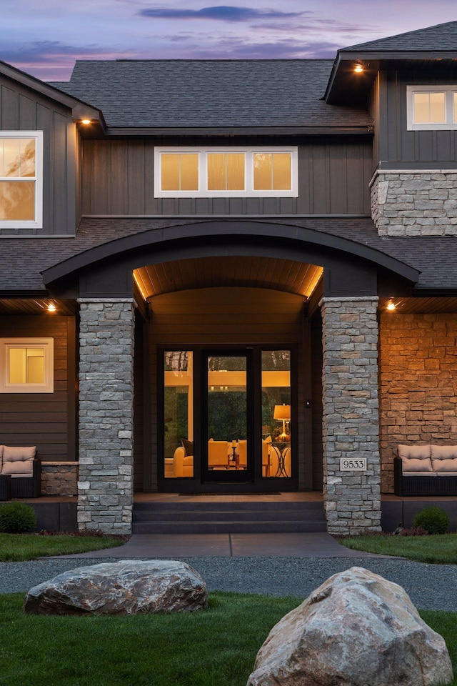 9533 Otchipwe Ave N, Stillwater, MN 55082 - exterior entry at dusk featuring board and batten siding, roof with shingles, and stone siding
