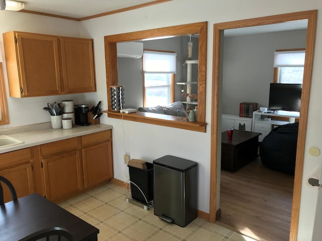 kitchen with a wall mounted air conditioner, crown molding, and plenty of natural light