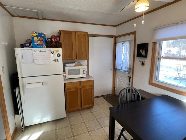 kitchen with white appliances, ornamental molding, and a textured ceiling