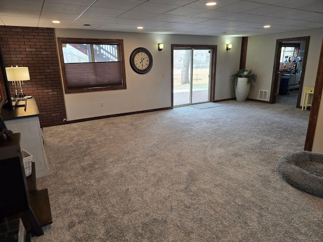 unfurnished living room with carpet flooring and a paneled ceiling