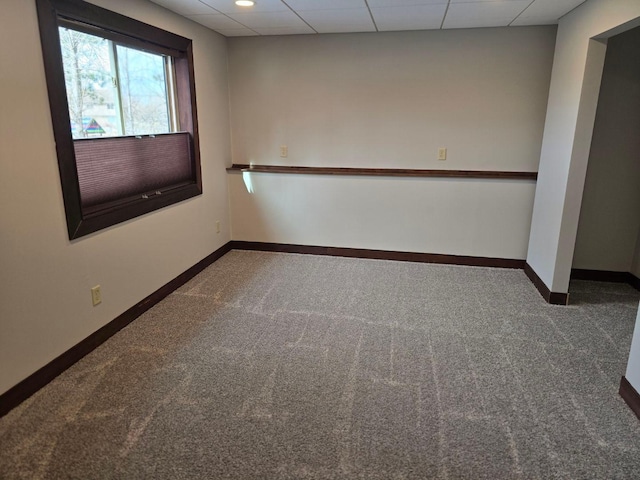 carpeted empty room with a paneled ceiling