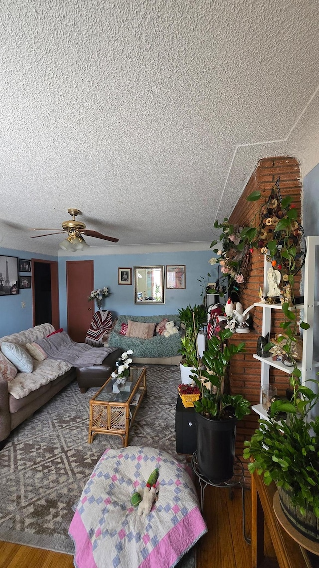 living room featuring ceiling fan, hardwood / wood-style floors, and a textured ceiling