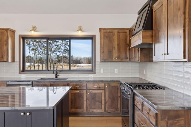 kitchen with range with gas cooktop, sink, dark stone countertops, backsplash, and custom range hood