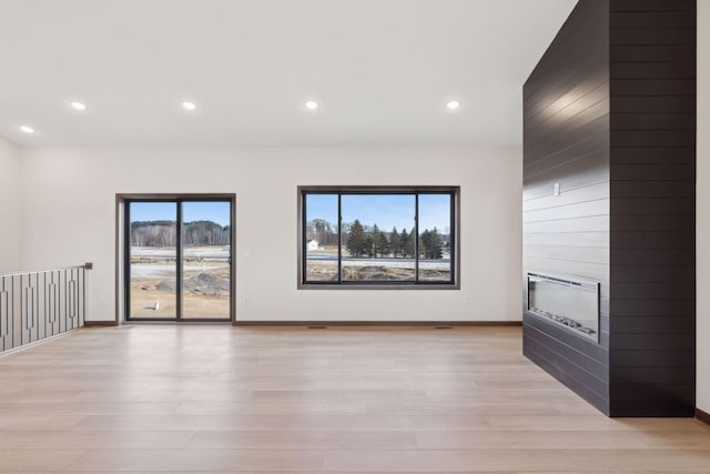21933 Edison Ct, East Bethel, MN 55011 - unfurnished room with a healthy amount of sunlight, a fireplace, and light hardwood / wood-style floors