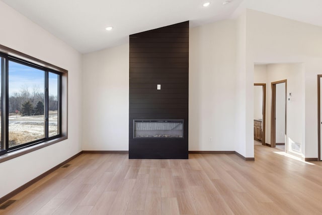 21933 Edison Ct, East Bethel, MN 55011 - unfurnished living room with lofted ceiling, light wood-type flooring, and a fireplace