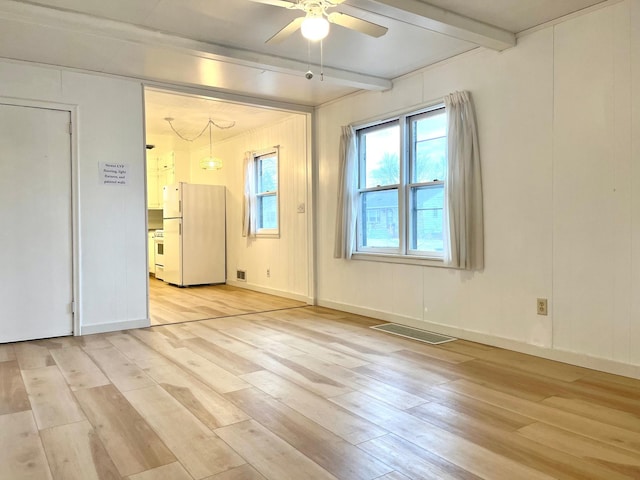 empty room featuring beam ceiling, light hardwood / wood-style floors, and ceiling fan