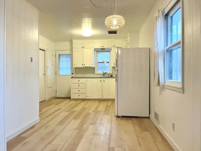 kitchen featuring sink, white cabinetry, light wood-type flooring, white refrigerator, and pendant lighting