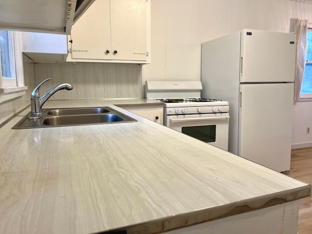 kitchen with white cabinetry, white appliances, and sink