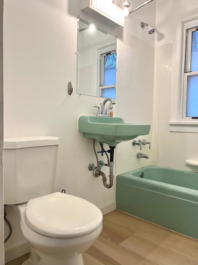 bathroom with shower / bathing tub combination, hardwood / wood-style floors, and toilet