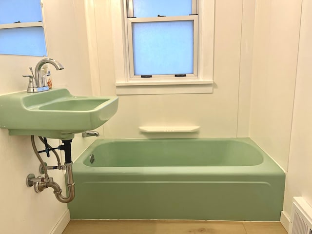 bathroom with a tub to relax in and sink