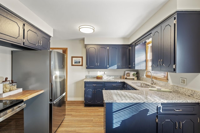 kitchen featuring electric range oven, stainless steel refrigerator, sink, light hardwood / wood-style floors, and kitchen peninsula