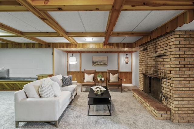 living room with wooden walls, coffered ceiling, a fireplace, light colored carpet, and beamed ceiling