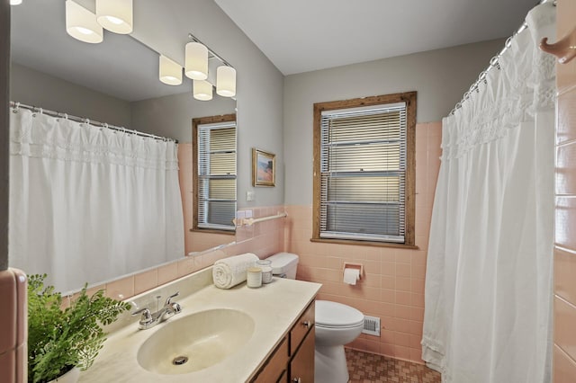 bathroom with vanity, tile walls, and toilet