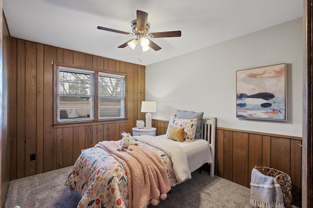 bedroom with carpet flooring, ceiling fan, and wood walls