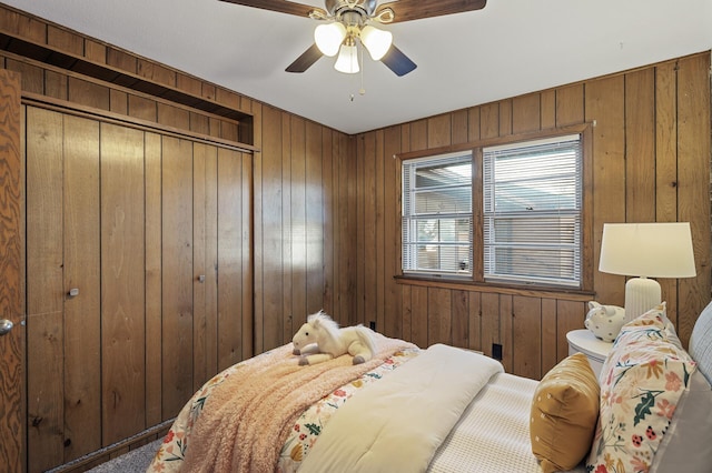 bedroom featuring ceiling fan, a closet, and wood walls