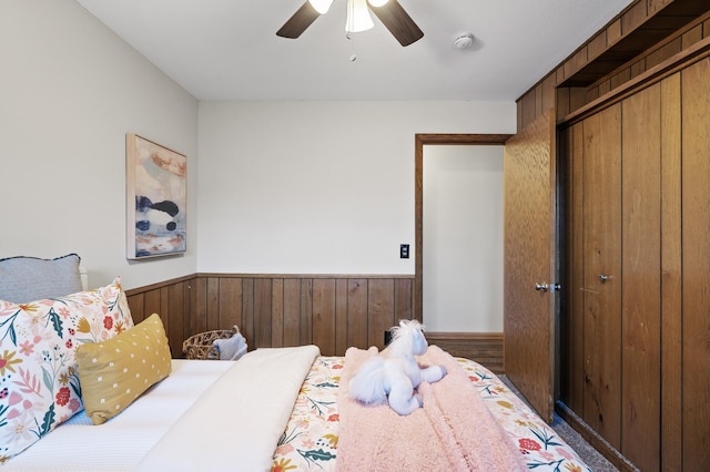 bedroom featuring a closet, ceiling fan, and wood walls