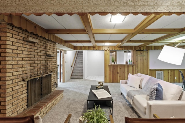 unfurnished living room with beamed ceiling, carpet floors, a brick fireplace, and wood walls