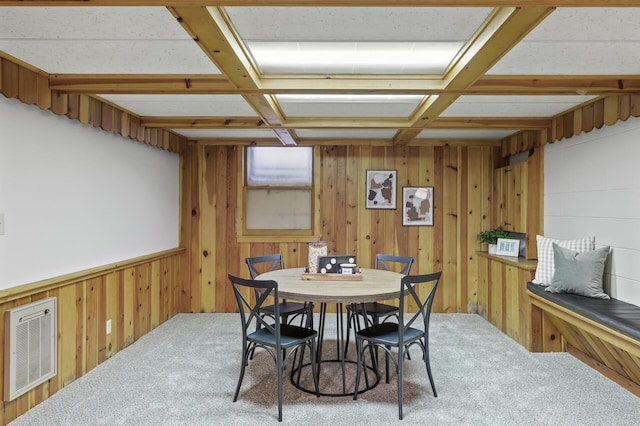 dining space featuring coffered ceiling, heating unit, and wood walls