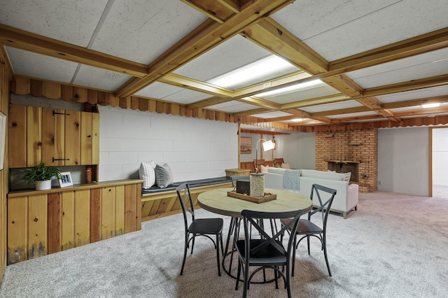 dining area with coffered ceiling, a brick fireplace, light colored carpet, and beamed ceiling