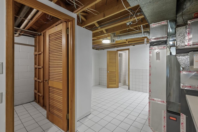 basement with heating unit and light tile patterned floors